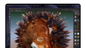 Close-up of the touchscreen MacBook Pro display running Cinema 4D with a spiked copper 3D head model and materials panel